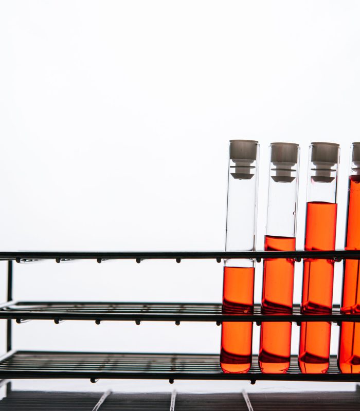 Orange chemicals in a science glass tube arranged on a shelf.