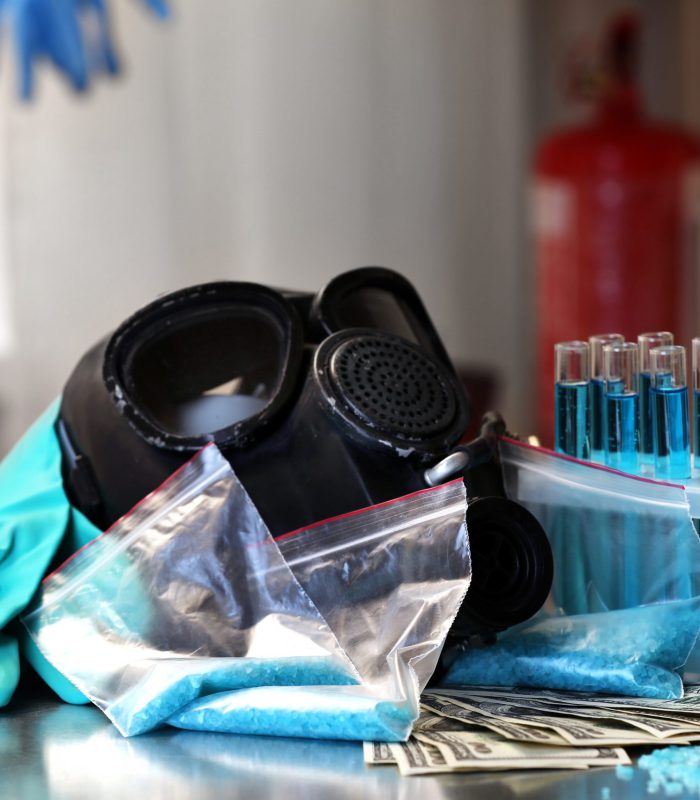 Drug laboratory: blue  methamphetamine and money on table close up